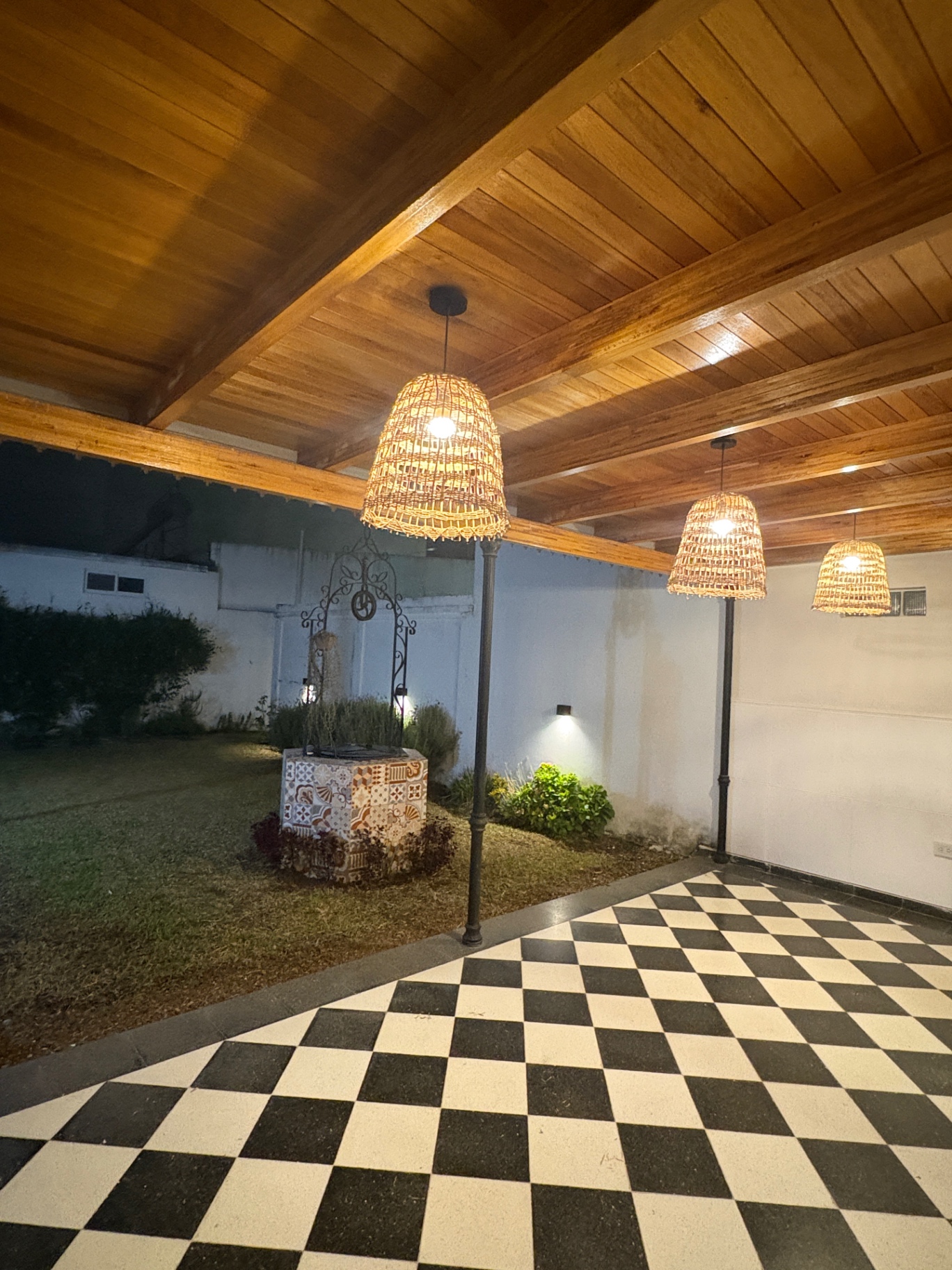 Patio interno de Centro ANPI con galería de madera, lámparas de fibra natural y piso damero.