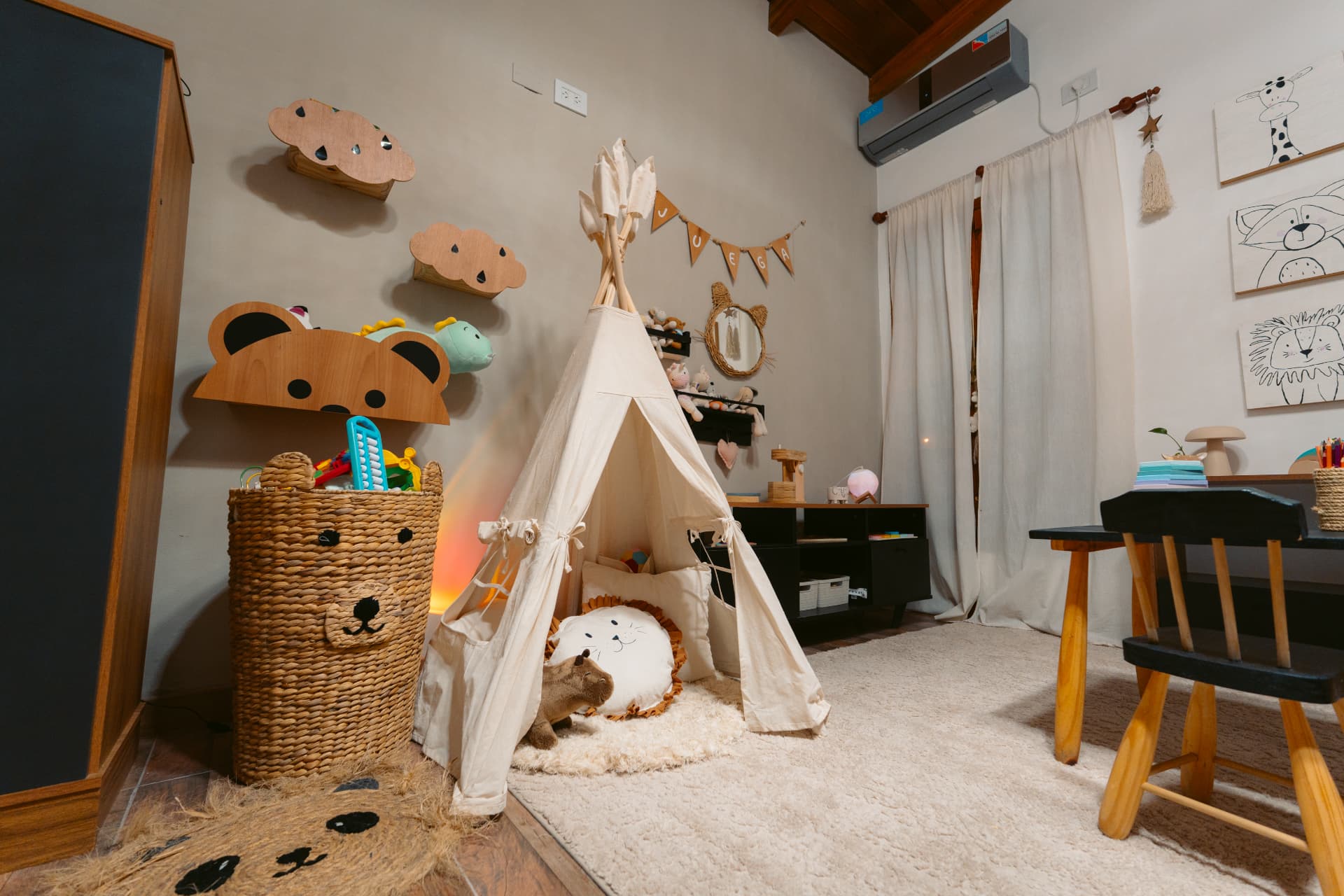 Rincón de juego de la sala de Centro ANPI: carpa tipi con almohadones y muñecos adentro, cesto de fibras con forma de oso lleno de juguetes y detalles de madera en la pared.