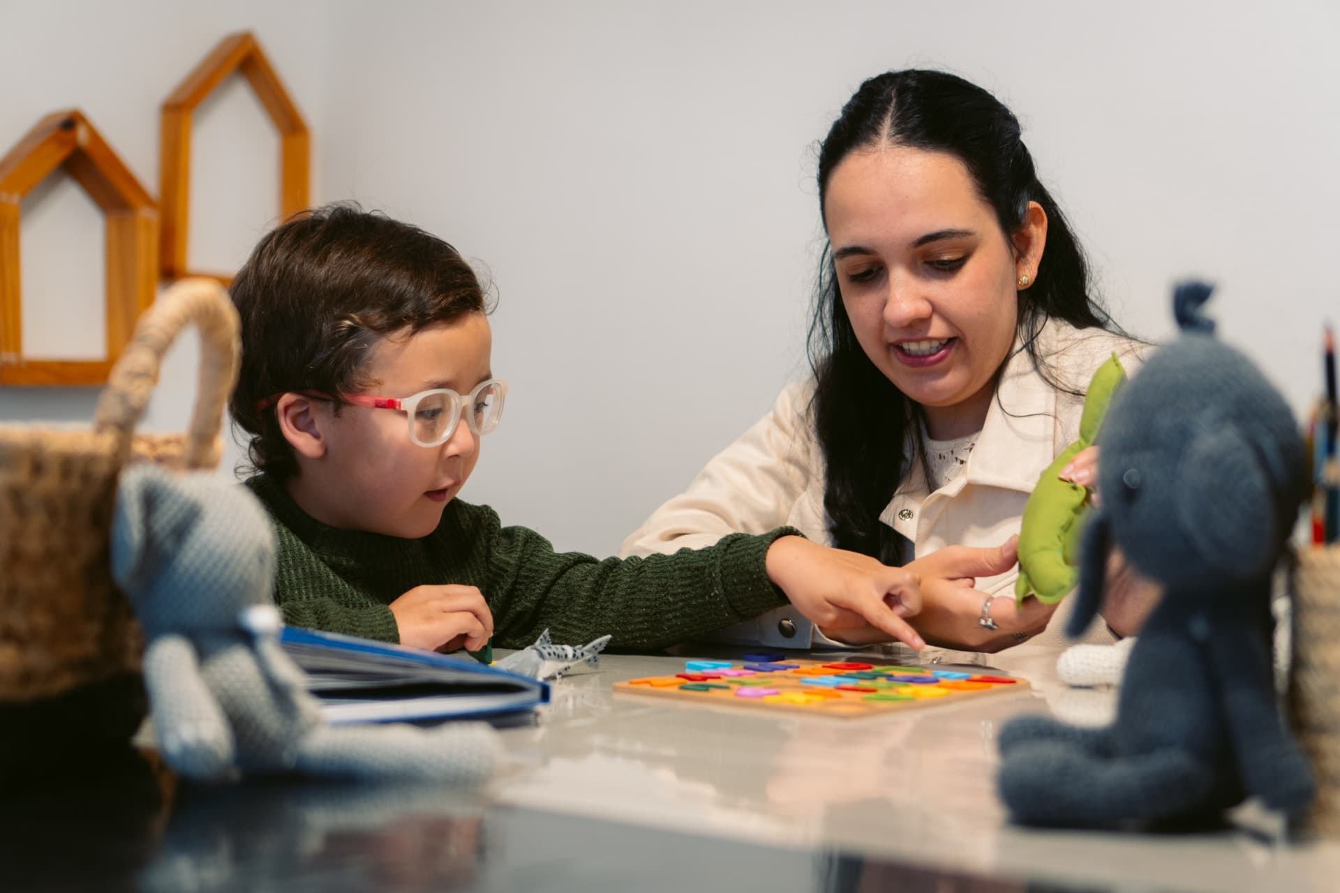Una profesional de Centro ANPI acompaña a un niño con materiales del abecedario y recursos lúdicos en el espacio de apoyo escolar del Centro.