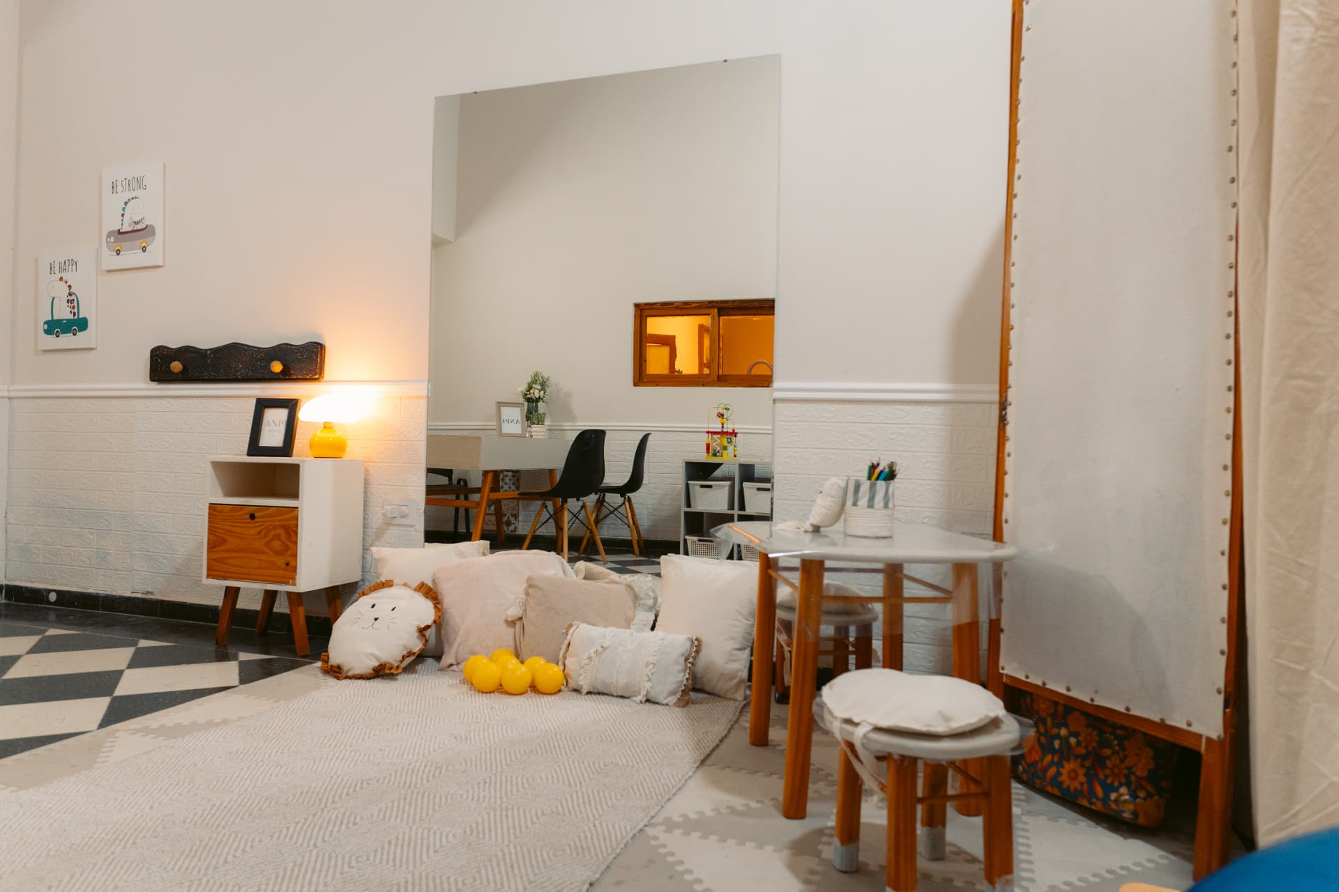 Sala equipada de Centro ANPI con espejo amplio, mesas, sillas, alfombra, almohadones y pelotas amarillas.