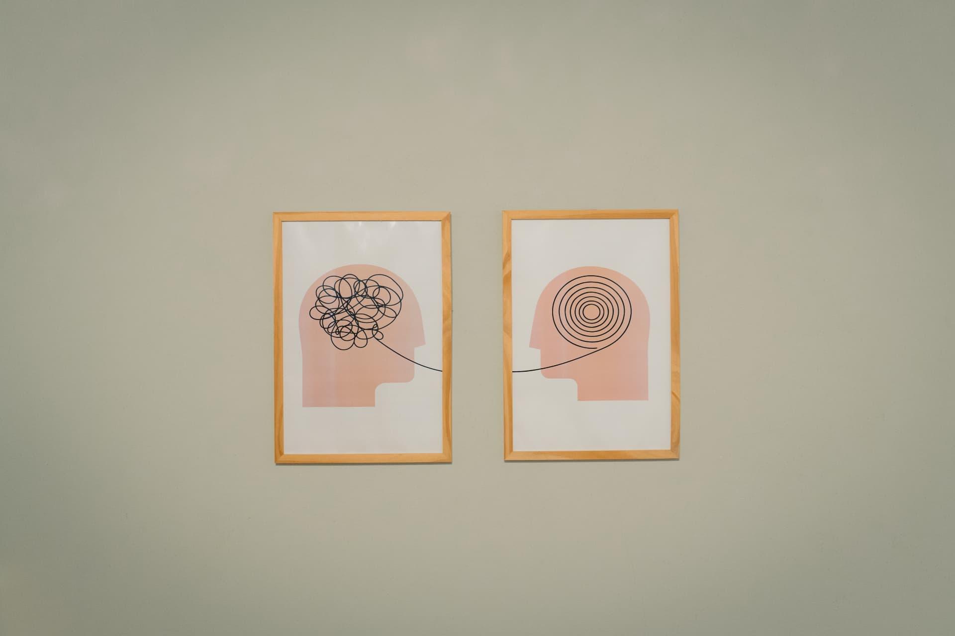 Cuadros de la sala de psicología de Centro ANPI: dos ilustraciones enmarcadas de perfiles con una línea que va de la maraña a la espiral, sobre una pared verde clara.