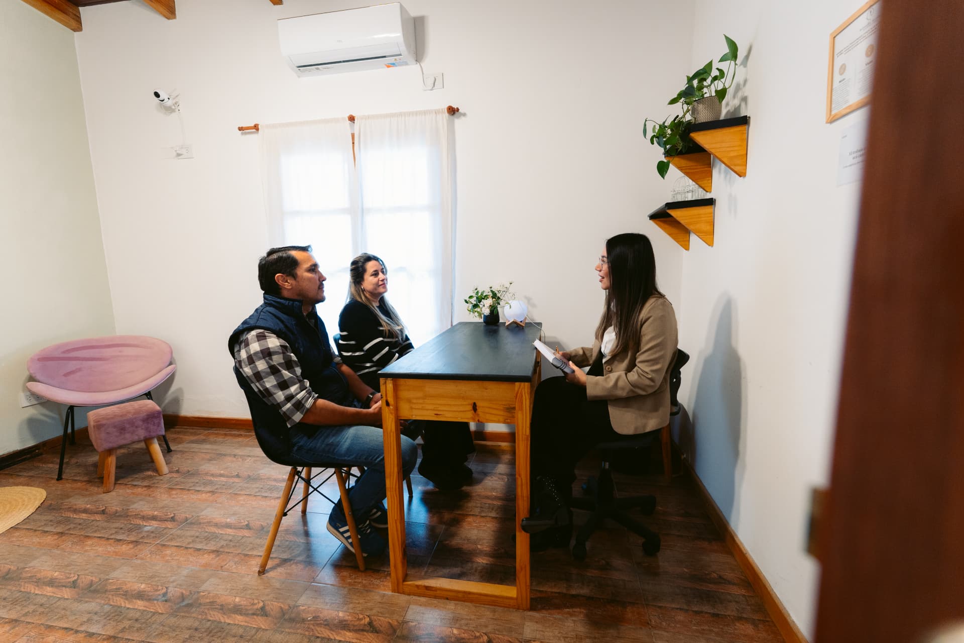 Una profesional de psicología de Centro ANPI acompaña una entrevista a una pareja sentada frente a su escritorio en el consultorio del Centro.